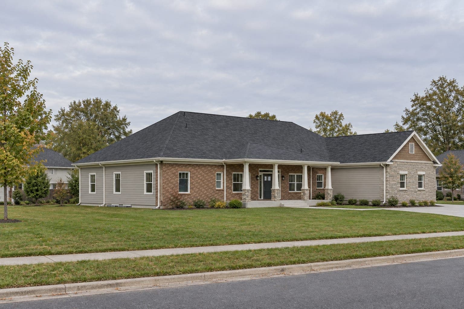 Luxury brick and stone ranch from the front corner, showing the hip roof and covered front porch