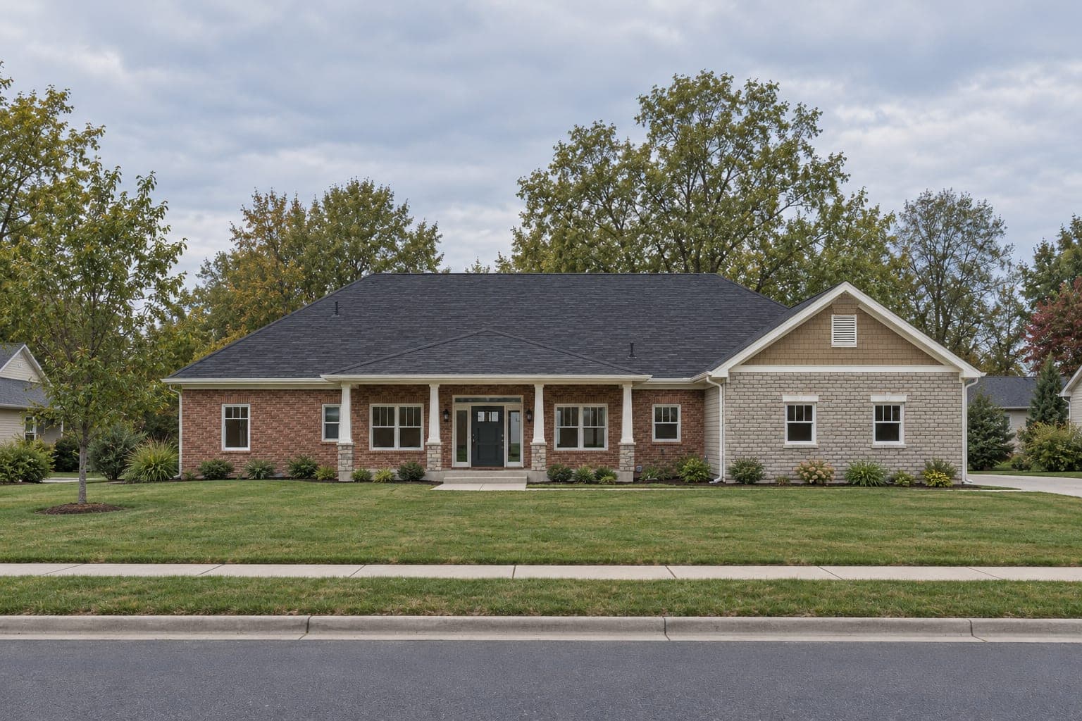 Front of a single-story luxury ranch with red brick, a stone-faced gable wing, a long covered porch on white columns and a black front door