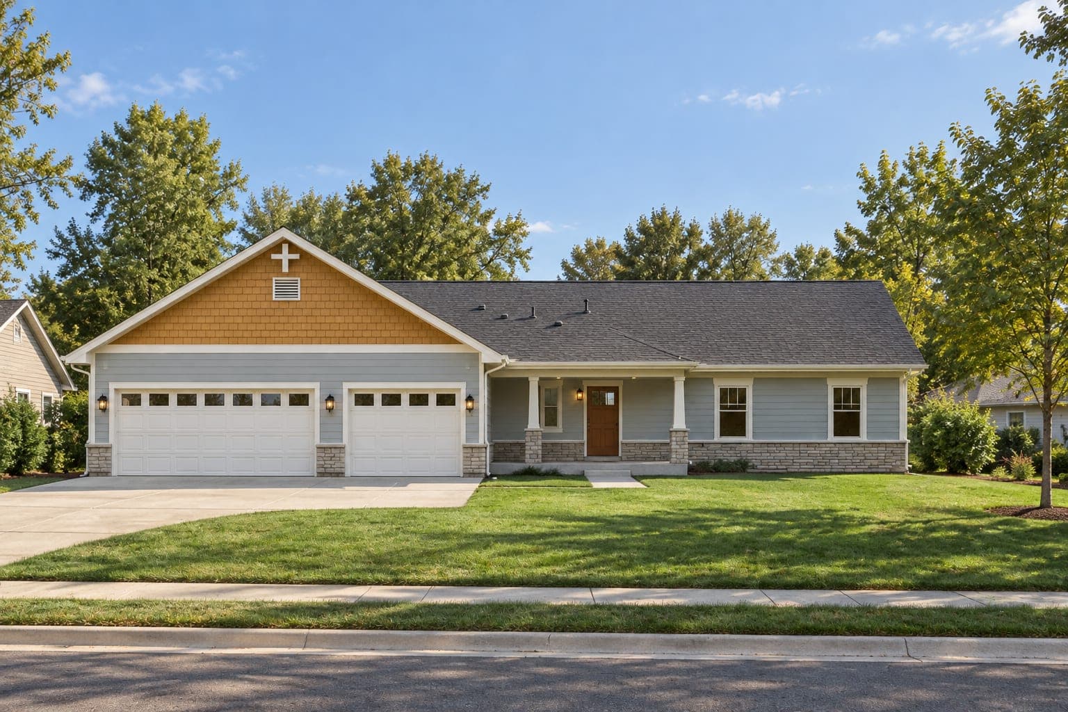 Front of a light blue Craftsman ranch with a cedar shake gable over a three-car garage, stone wainscot and a covered entry