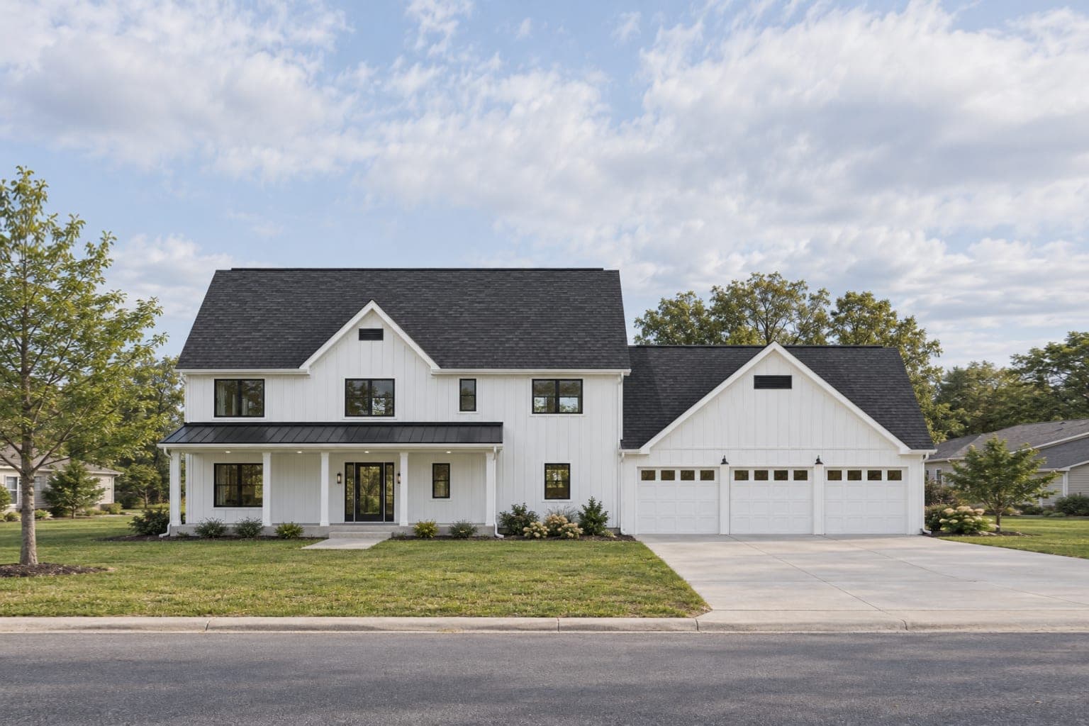 Front of a white board-and-batten two-story modern farmhouse with black windows, a metal-roofed front porch and a three-car garage